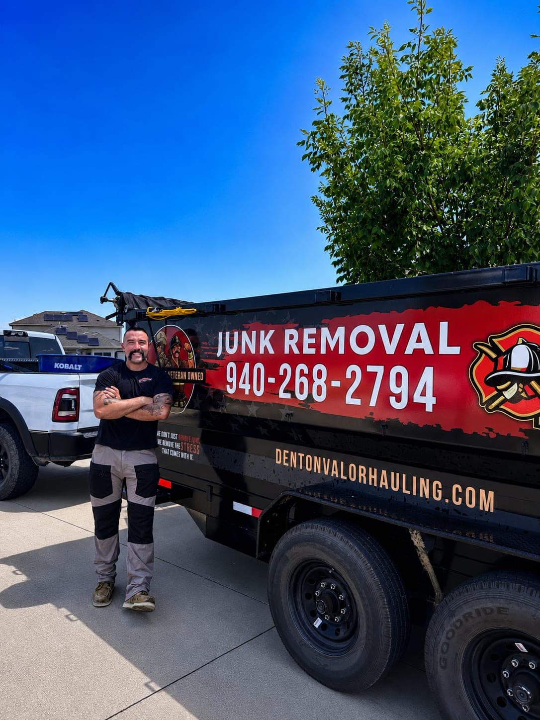 Damon Ortega standing beside his black dump trailer lettered Junk Removal and (940) 268-2794