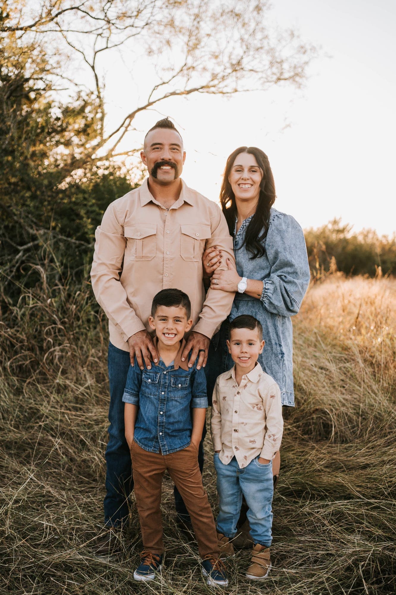 Damon Ortega with his wife and their two sons standing in tall grass